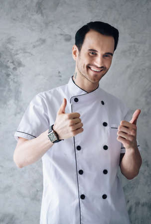 The chef is handsome, smiling and confident with a plastered background.の写真素材
