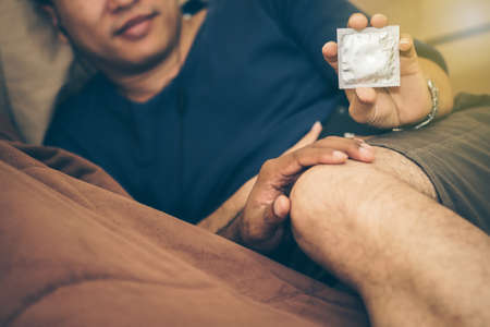 Men,gay,couples Holding a condom for self-protection. Concept  Sexually Transmitted Diseases Prevention.の写真素材