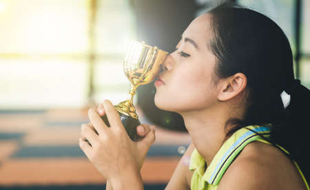 Asian female athlete is kissing her trophy with pride in success.の写真素材
