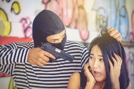Thieves used a gun to threaten a woman is scared to rob valuables.の写真素材