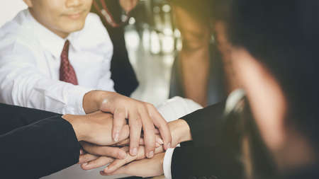 Young businessmen join hands together to conduct business together for unity as a team. Focus on hands and other parts blurred background.の写真素材