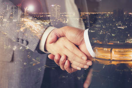 Double exposure Business people are making a success and a handshake in city night.Business success concepts.の写真素材