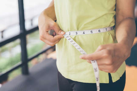 Teenage girls use their own waist measurement straps. To control the size and shape of yourself after exercise.の写真素材