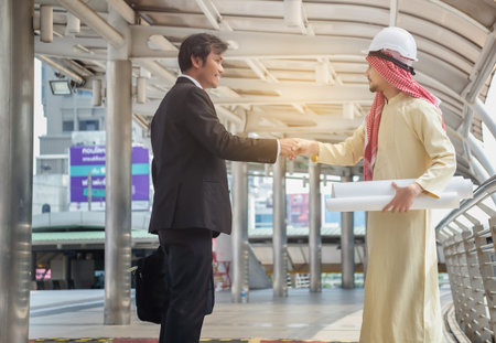 Asian businessmen and Arab architects have handshake agreed on a joint plan.