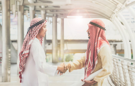 Arab businessmen shake hands and accept business deals for teamwork.