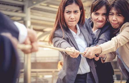 Business women help pull the rope against the Business Man. Concept is like to work as a team in the...