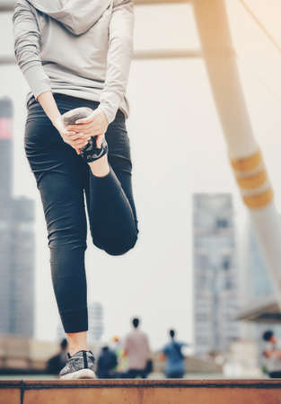 An Asian woman is warming herself to exercise in a big city.Healthy Fitness Concept.の写真素材