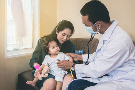 An Asian doctor is checking the symptoms of a sick girl and having her mother with her.の写真素材
