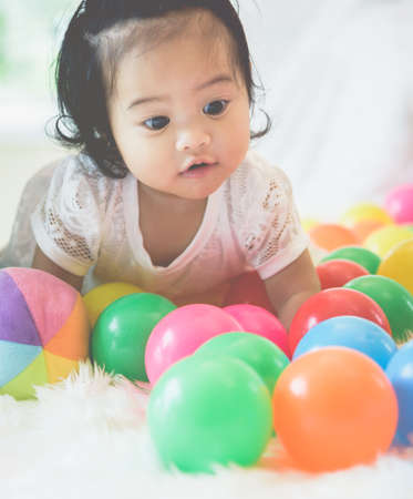 An Asian baby girl is playing in her bed with a happy expression.の写真素材