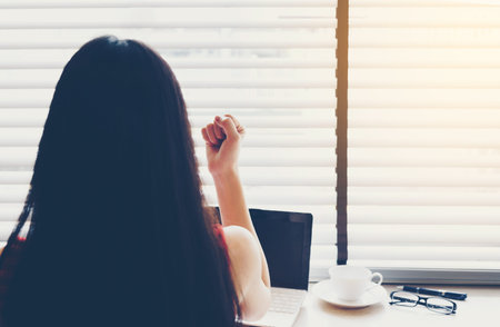 Successful Asian business woman raises her hands with delight at her work.Focus on the hand