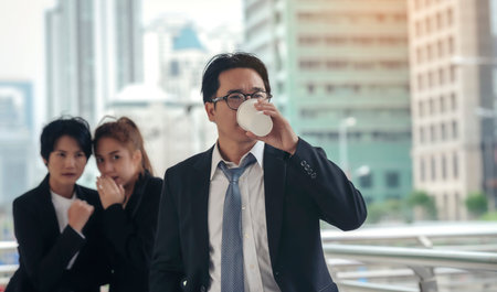 Businessman is being hit by a colleague gossiping behind him.の写真素材