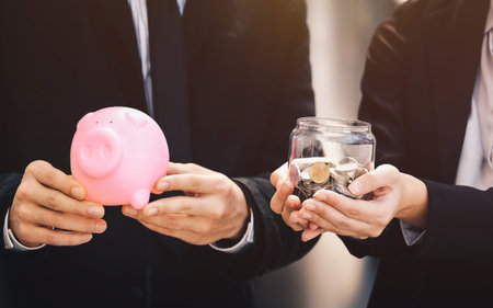 Businessmen, men and women holding a piggy bank, coins to save money. Financial and investment conception.の写真素材