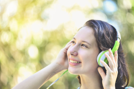 Beautiful women are listening to music with their eyes closed, and white,green headphones are...