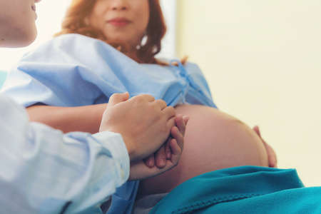 The man is her husband are holding hands and comforting, to give encouragement to his pregnant wife.の写真素材