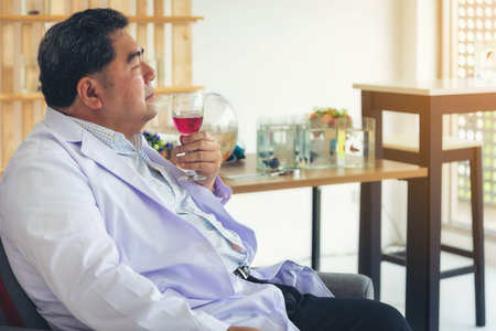 The middle age man resting and enjoyed a glass of red wine in his hand.