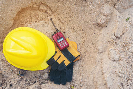 Yellow helmets, gloves, radio communication and shovel on the sand pile.の写真素材