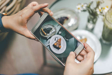 Woman's hand was photographed cake by her smartphone to get into social media.の写真素材