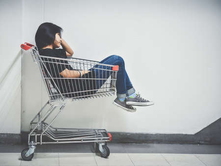 A teenage girl is sitting in a trolley with a bored gaze.This image is Soft Focus.の写真素材