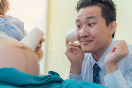 The man that her husband was listening to the movements of the child in the belly of a pregnant woman happilyの写真素材