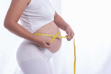A pregnant woman is measuring size around her belly.の写真素材
