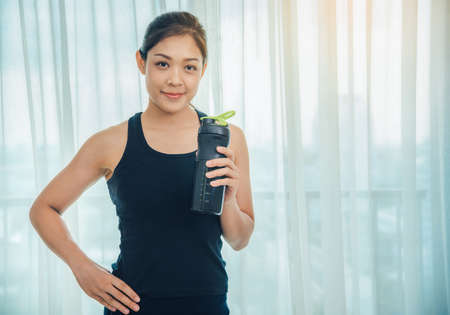 A woman holding a bottle of protein supplements on muscle drink to strengthen health care to vigorous and beautiful.の写真素材