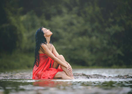 Asian woman in a red bathrobe and enjoy nature in the wild.の写真素材