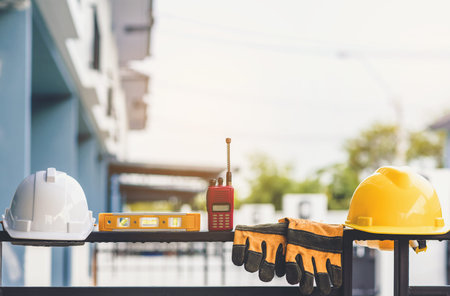 White and yellow helmet  with construction water,gloves and radio that are placed on steel house...