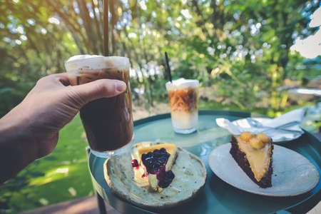 Man's hands holding iced coffee with cakes are naturally beautiful background.の写真素材