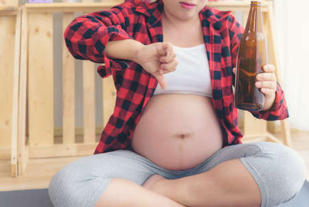 Pregnant woman drinking beer, which is very bad for the health.の写真素材