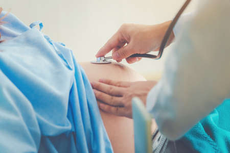 Pregnant woman lying in bed waiting for childbirth with medical supervision in a hospital.の写真素材