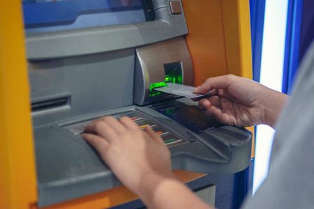 Woman pressing cash card at ATM cabinet.This image is soft Focus.