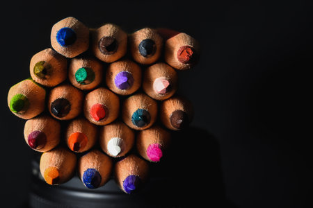 Many wooden crayons that have been used in the dark background are macro images.