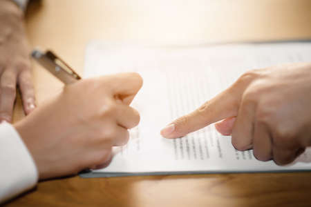 The hand of a business man is using the index finger to let the customer sign the contract, contract, business agreement.の写真素材