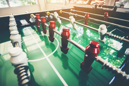 An old wooden football game table with players made of red and white wood.