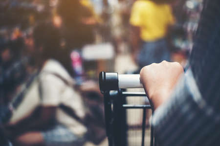 Asian woman's hand with supermarket, trolley and many objects that are blurred background.の写真素材