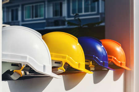 White, yellow and other colored safety helmets for workers' safety projects in the position of engineers or workers on concrete walls in the city.の写真素材