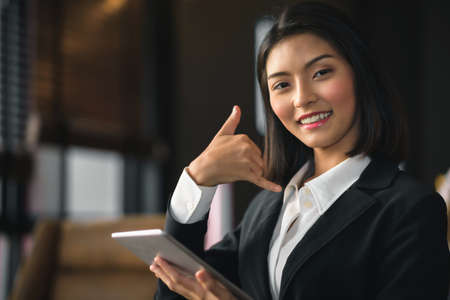 An Asian businesswoman holding a tablet inviting her to come back.の写真素材