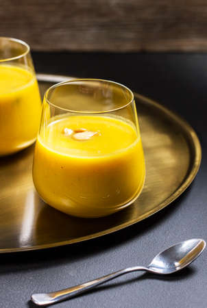 pumpkin soup in a glass on a golden plateの写真素材