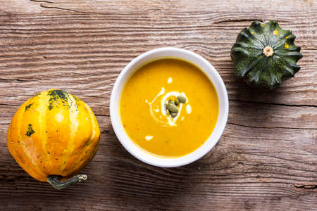Pumpkin soup with seeds and cream on a wooden tableの写真素材