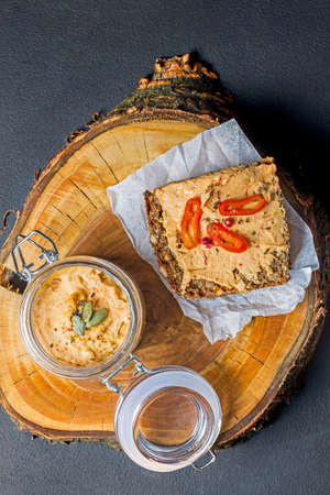 A slice of bread with homemade pumpkin puree on a wooden table, view from the topの写真素材