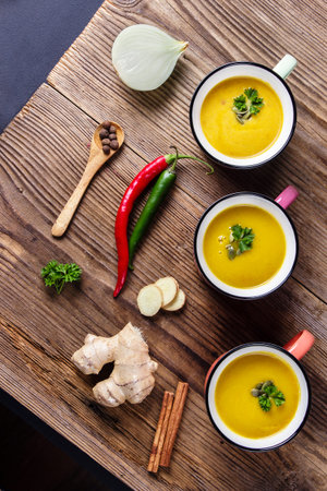 Pumpkin soup in enamel mugs, pumpkin seeds and parsley, view from topの写真素材