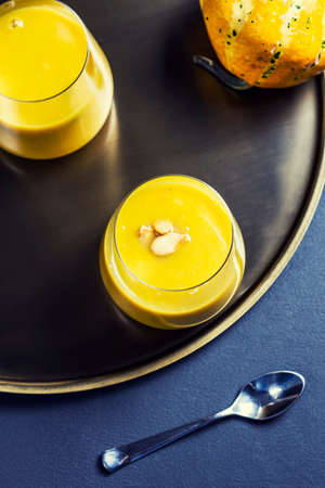 Pumpkin soup in a glass on a golden plate, view from the topの写真素材