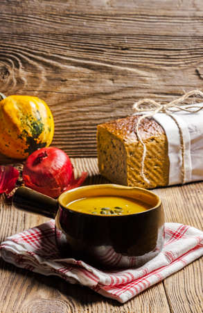 Pumpkin soup in a ceramic bowl with seeds, bread and onionの写真素材