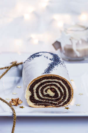 Christmas poppy seeds cake on a white plate with candles in the backgroundの写真素材