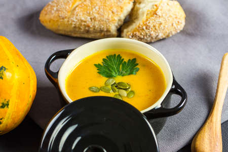 Pumpkin soup with seeds and parsley in a rustic ceramic bowlの写真素材