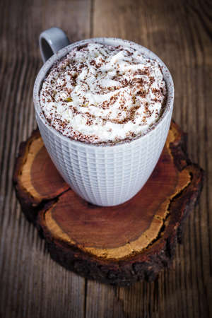 A cup of hot cocoa on a slice of woodの写真素材