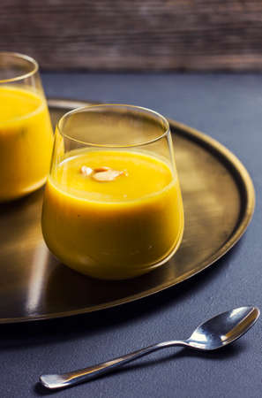 Pumpkin soup in a glass on a golden plateの写真素材