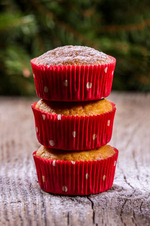 Muffins sprinkled with powdered sugar on a wooden table and pine in the backgroundの写真素材