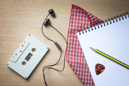 Cassette ,headphones and blank notebook on wood for songwriter background with vintage toneの写真素材