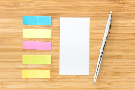 Notepaper, sticky notes and pen put on wooden desk